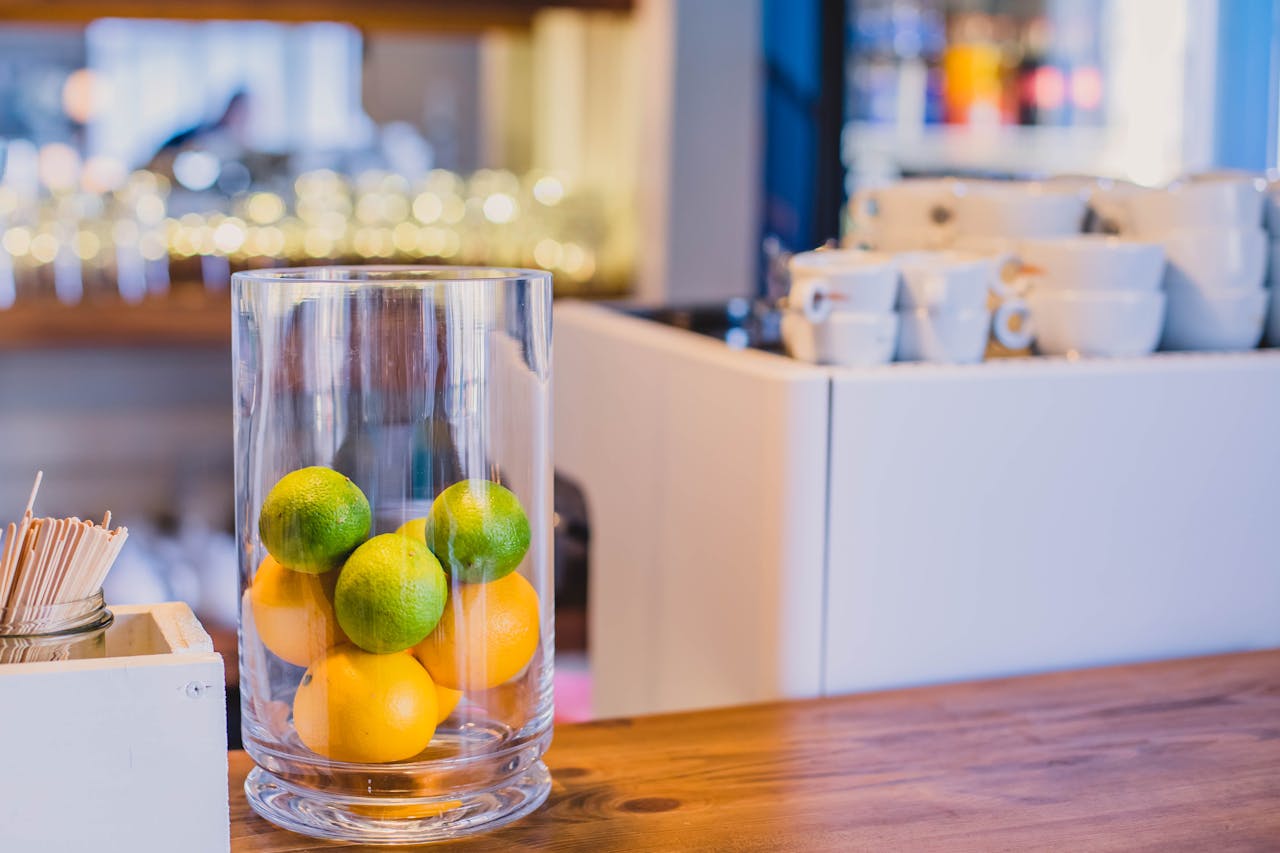 A stylish café counter with limes and oranges in a glass container, providing a fresh and vibrant look.