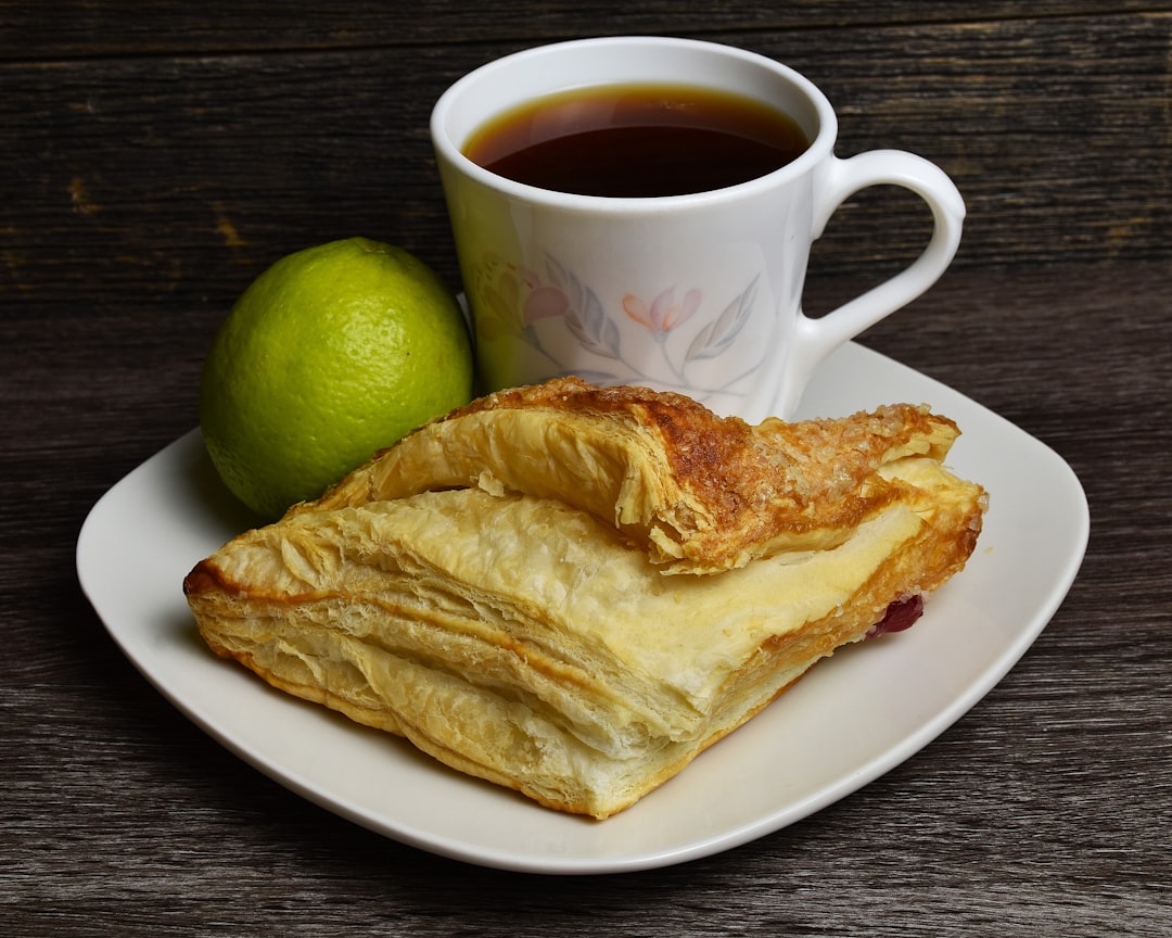 a-white-plate-topped-with-pastry-next-to-a-cup-of-tea-a-cwbosts8